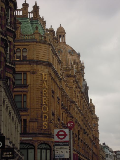 The image depicts the upper facade of a historic sandstone building with intricate architectural detailing, including arched windows, decorative cornices, and ornamental stonework. The building featur